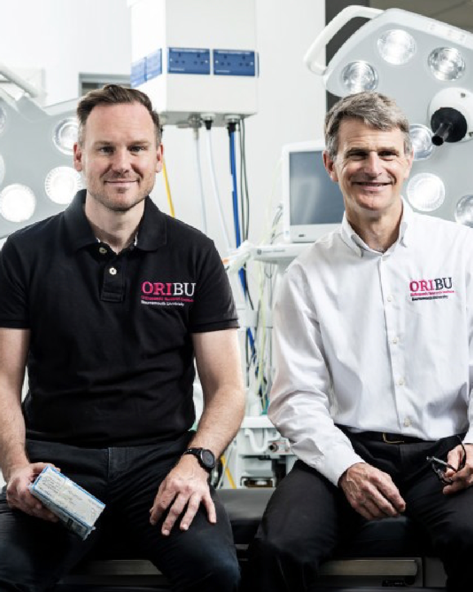 Professors Robert Middleton and Tom Wainwright sitting in an operating theatre